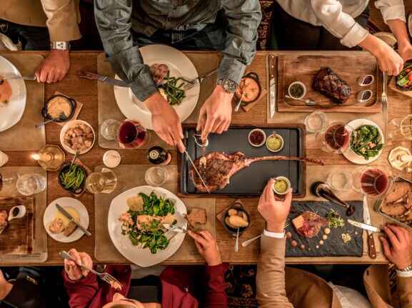 Top-Shot auf einen üppig gedeckten Tisch, an dem mehrere Personen sitzen und essen.