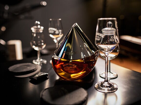 Eine Flasche Bowmore ARC-52 aus der Kooperation mit Aston Martin steht auf einem Tisch mit speziellen Whisky-Gläsern