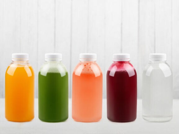 Unterschiedlich farbige Fruchtsäfte in Flaschen auf weißem Unter- und Hintergrund