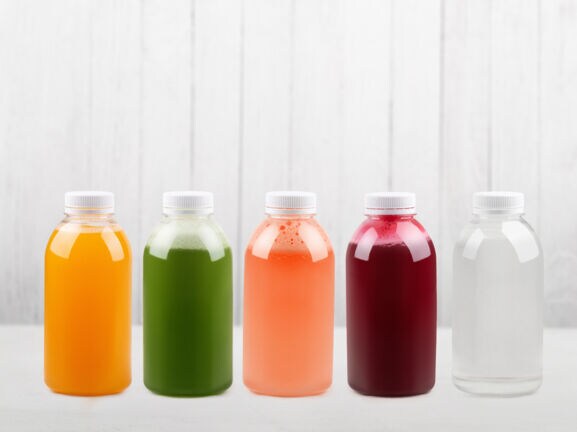 Unterschiedlich farbige Fruchtsäfte in Flaschen auf weißem Unter- und Hintergrund