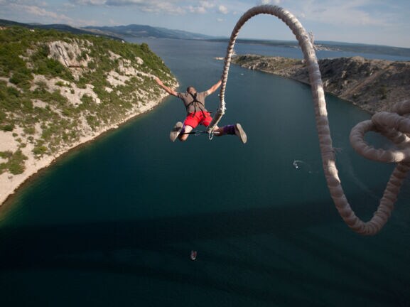 Eine Person springt an einem Bungeeseil in die Tiefe.