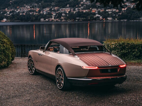 Der Rolls-Royce Boat Tail steht im Abendlicht vor einem See