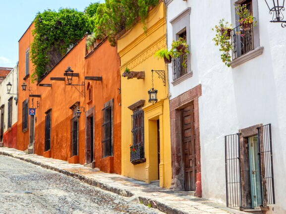 Straße mit Kopfsteinpflaster und Gebäude mit bunter Fassade. 