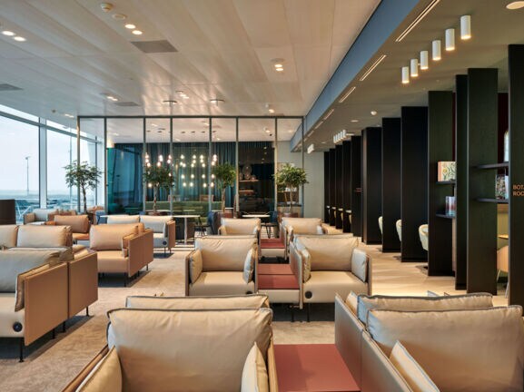 Moderne Flughafenlounge mit Sesseln aus beigem Stoff.