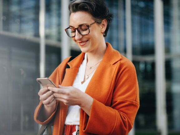 Elegante Geschäftsfrau schaut auf ihr Smartphone