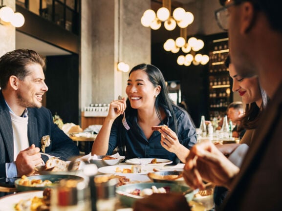Vier fröhliche Menschen an einem Tisch im Restaurant.