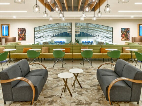 Moderne, elegante Flughafen-Lounge mit unterschiedlichen Sitzgelegenheiten und einem Panoramafenster mit Blick in den Terminal.