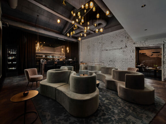 Gastraum in edlem Design, mit geschwungenen Polstermöbeln und einem Ambiente in Industriestil.