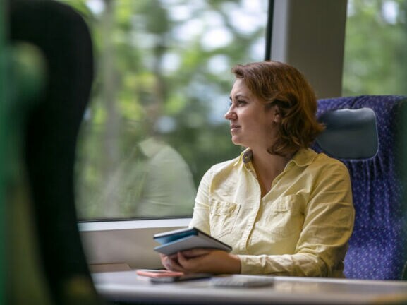 Eine Geschäftsfrau reist klimafreundlich im modernen Zug.