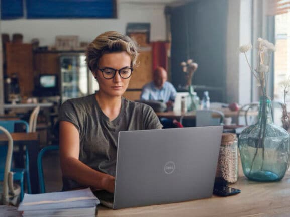 Eine Frau arbeitet in einem Café am Laptop.