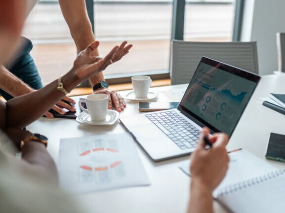 Das Bild zeigt eine Nahaufnahme eines Laptops während einer Besprechung des Buchhaltungsteams.