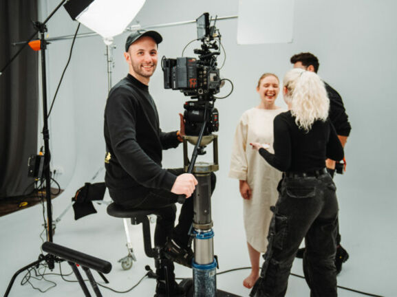 Fotografie von Dennis Schmelz an der Kamera im Filmstudio.