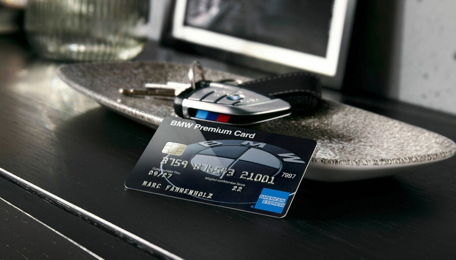 Auf einem Sideboard steht eine Schale, in der ein Autoschlüssel liegt, davor befindet sich die BMW Card Carbon.