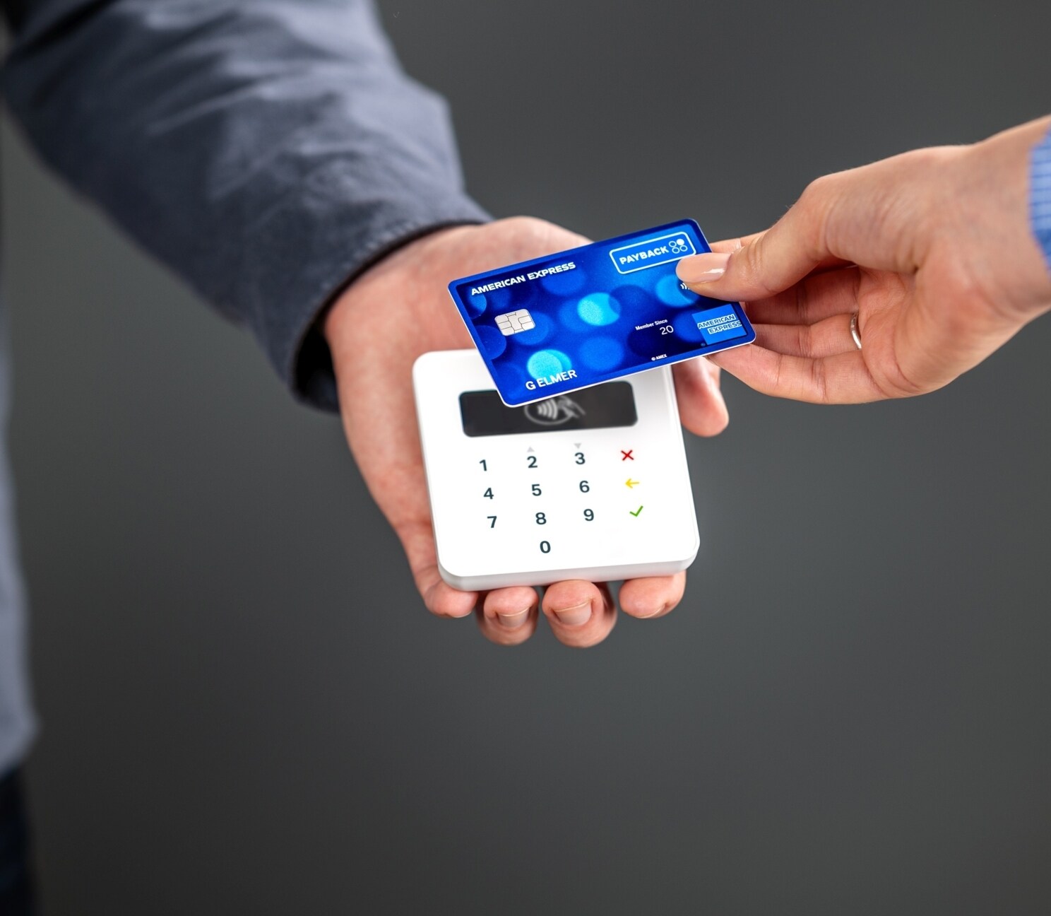 Eine Person hält ihre PAYBACK Amex Karte an ein Bezahlgerät.