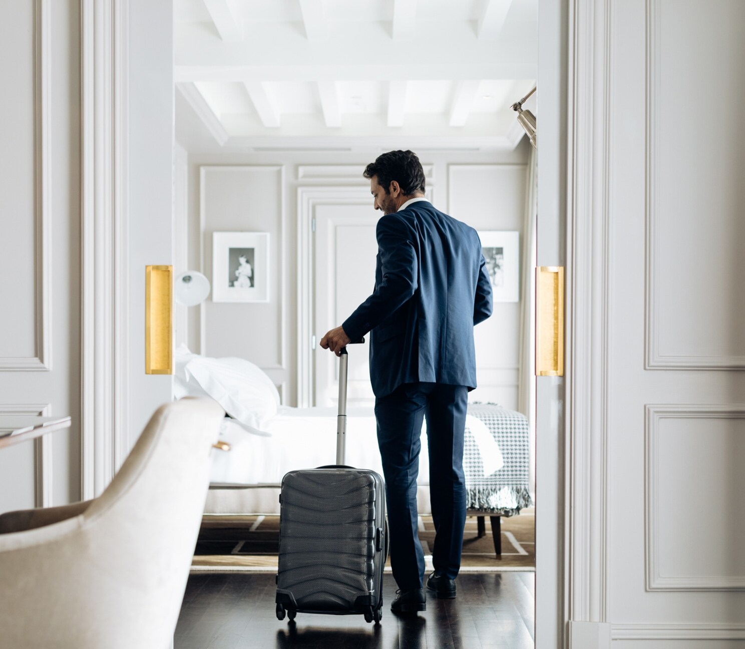Businessman with wheeled luggage in suite