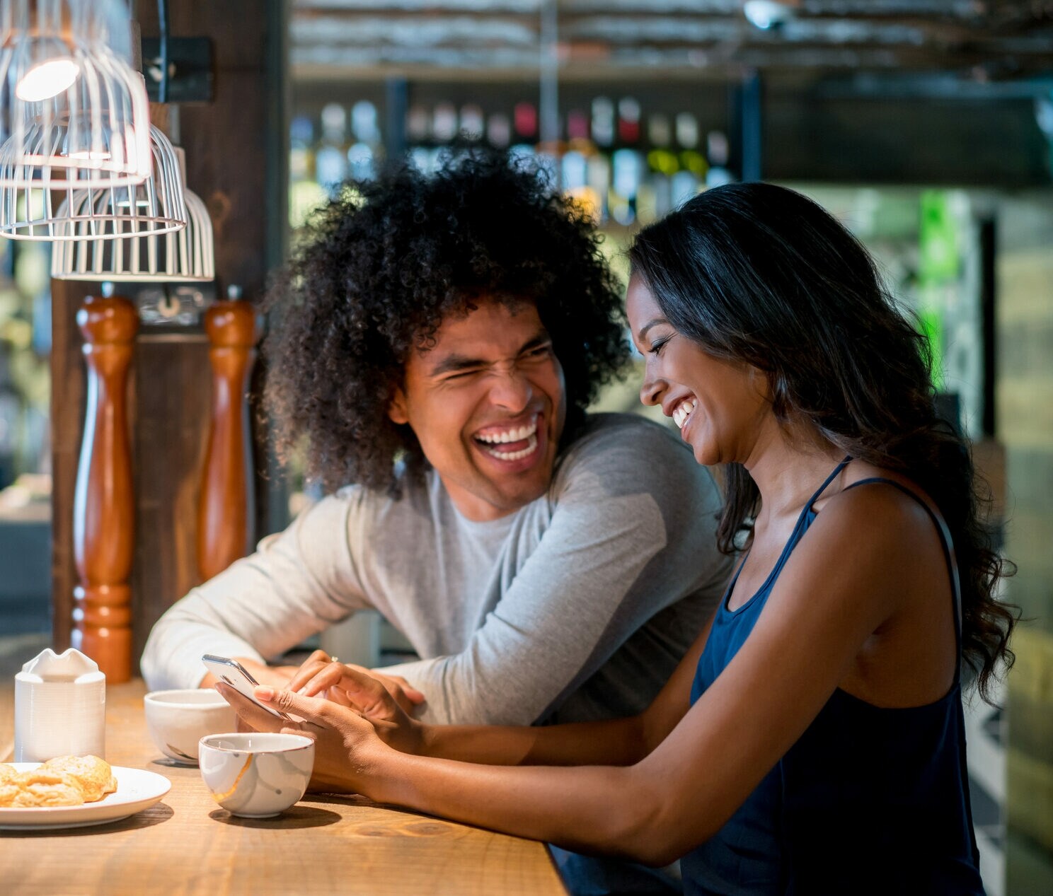 Zwei Personen sitzen in einem Café und lachen sich an.