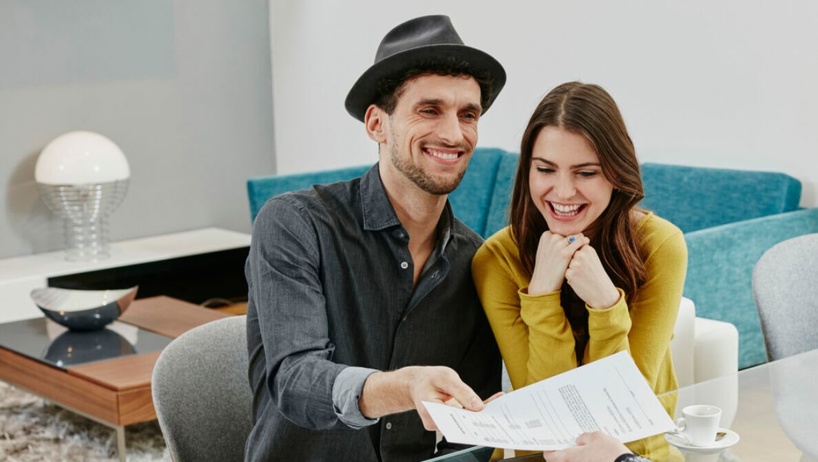 Ein glückliches Paar übergibt ein Dokument einer Frau