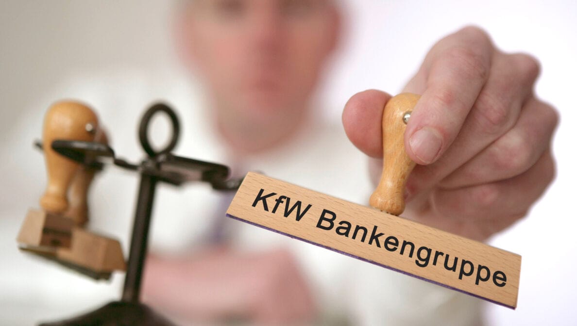Mann hält Stempel mit der Aufschrift KfW Bankengruppe in der Hand.