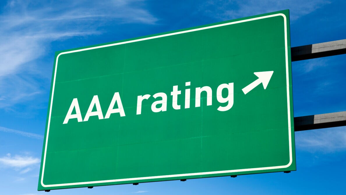 Ein grünes Verkehrsschild vor blauem Himmel mit der Aufschrift “AAA Rating” und einem Pfeil.