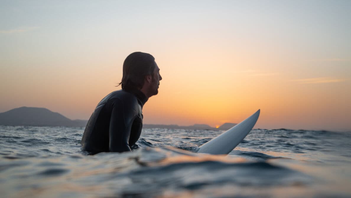 Seitenansicht eines auf einem Surfbrett sitzenden Mannes im Meer