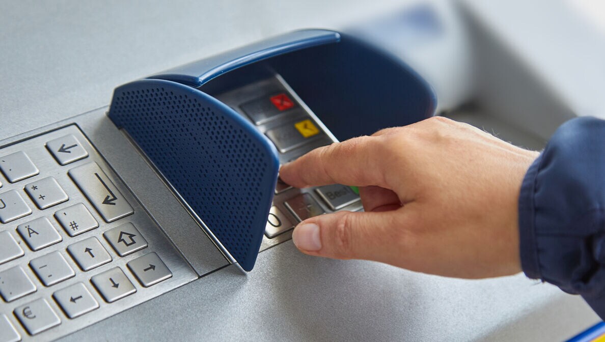 Eine Hand beim Eintippen einer PIN am Geldautomaten