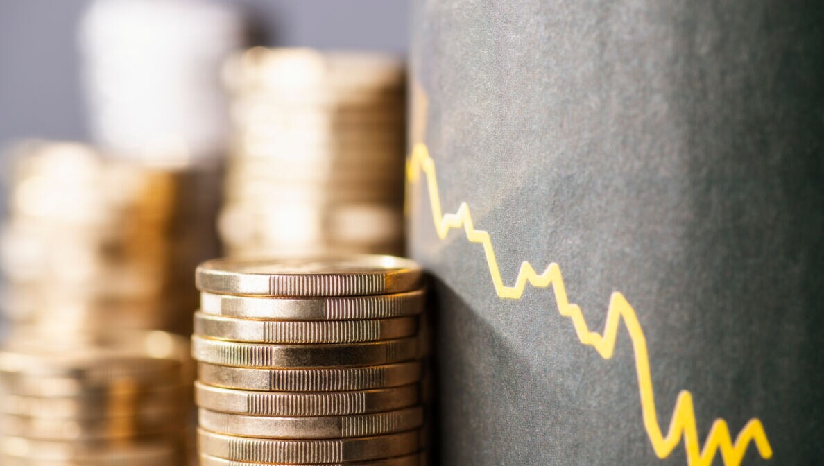 Münzstapel vor einer gezeichneten abfallenden Renditekurve