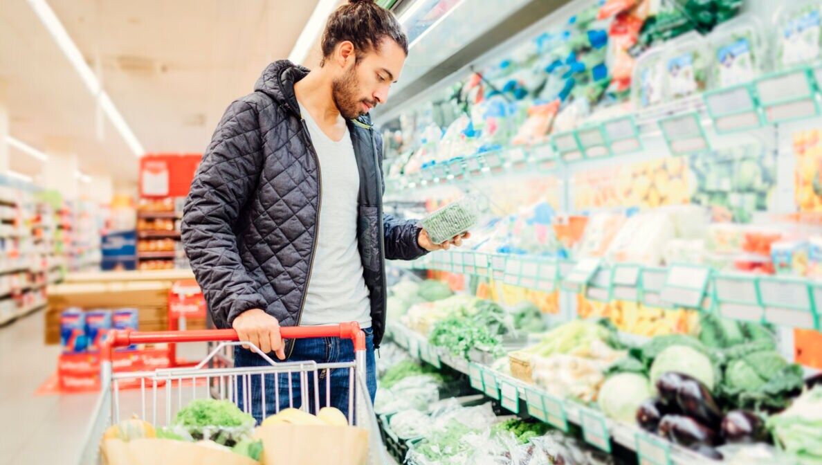 Ein junger Mann vor einem Gemüseregal in einem Supermarkt