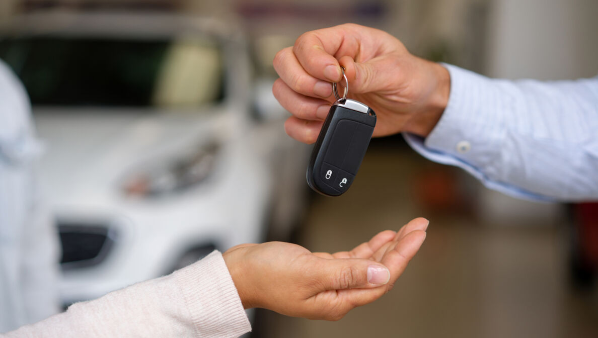 Zwei Person, deren Hände zu sehen sind, bei der Übergabe eines Autoschlüssels