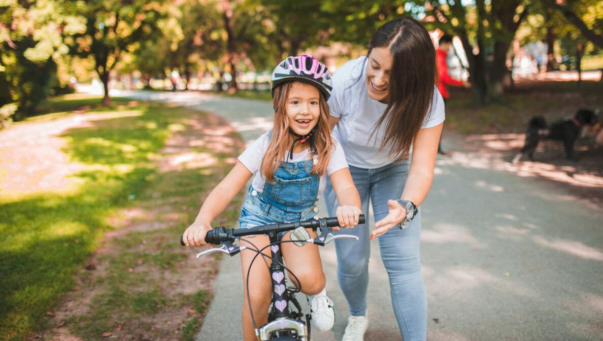 Mutter bringt ihrer Tochter das Fahrradfahren im Park bei