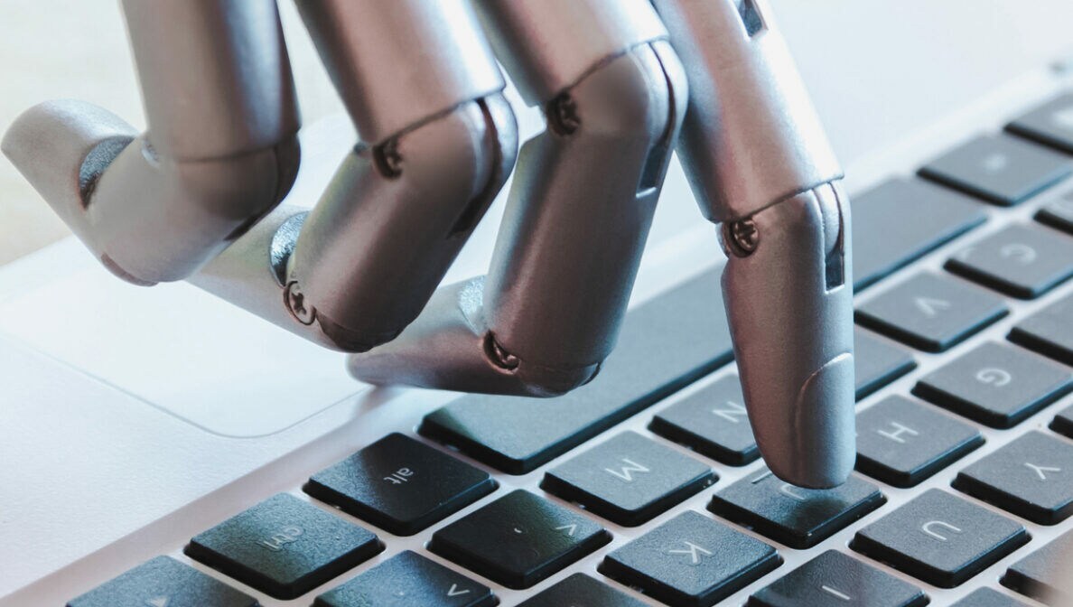 Eine Roboterhand, die auf einer Laptoptastatur tippt