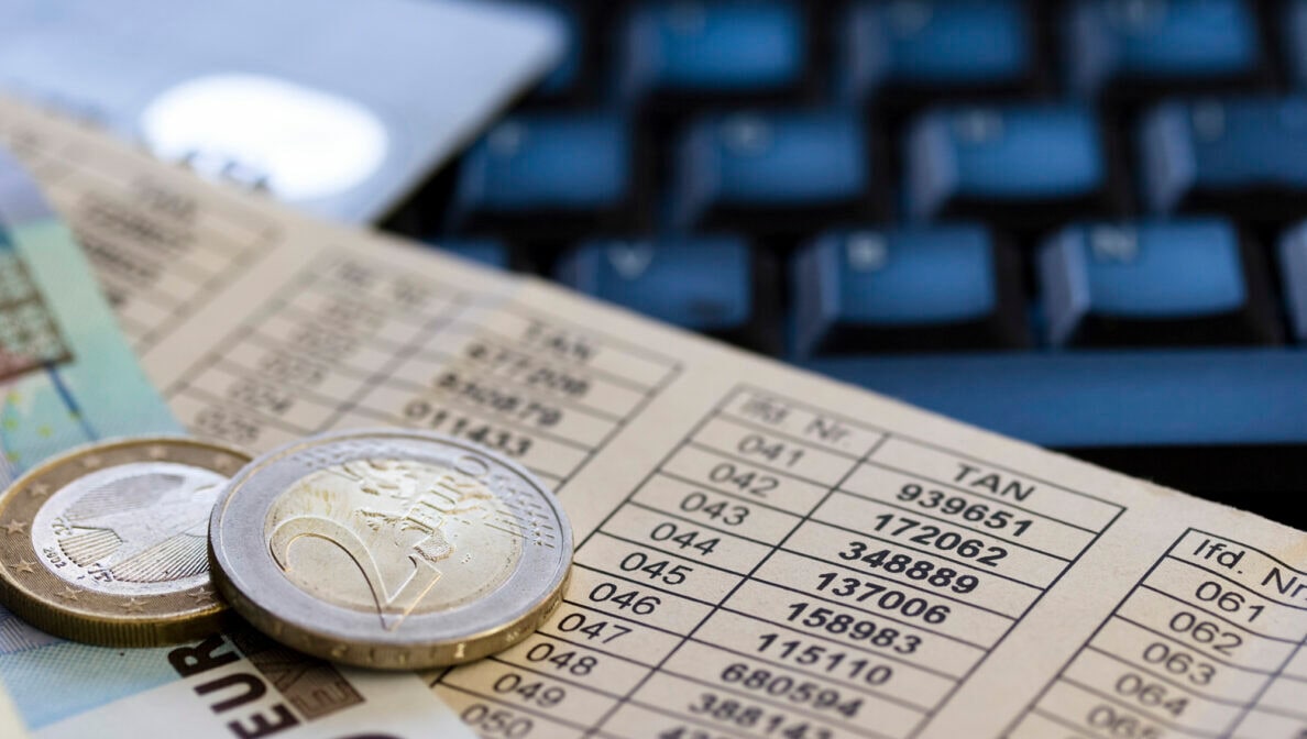 Euromünzen und ein Euroschein liegen auf einem Zettel, auf dem Zahlen in Tabellenform stehen