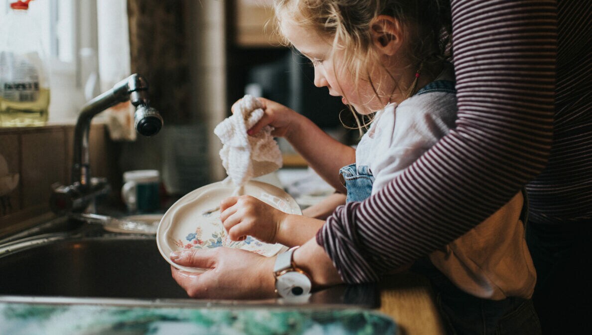 Ein kleines Kind wäscht zusammen mit einer Person ab
