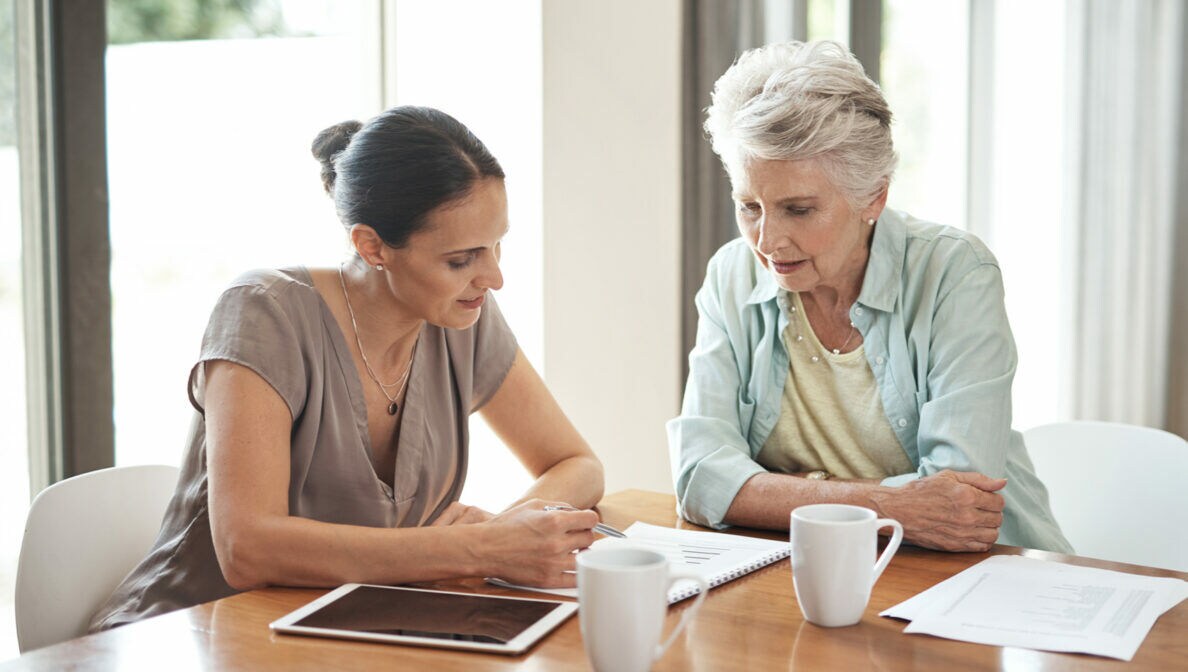 Eine ältere und eine jüngere Frau sitzen am Tisch und lesen Dokumente