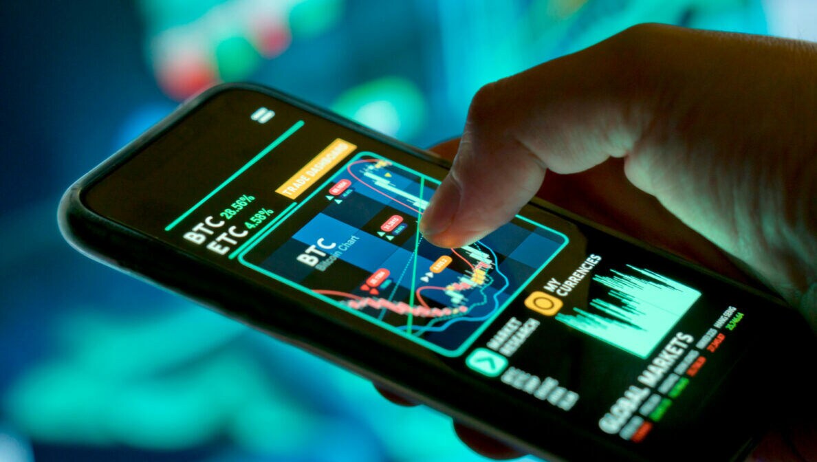 Ein Handy, auf dessen Display Bitcoin-Kurse angezeigt werden