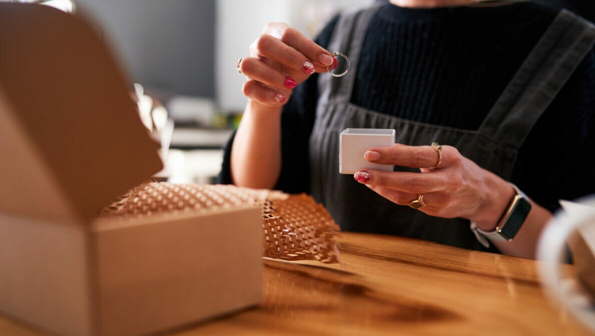 Nahaufnahme einer Person, die dabei ist, einen Ring in eine Schachtel zu legen und für den Versand vorzubereiten