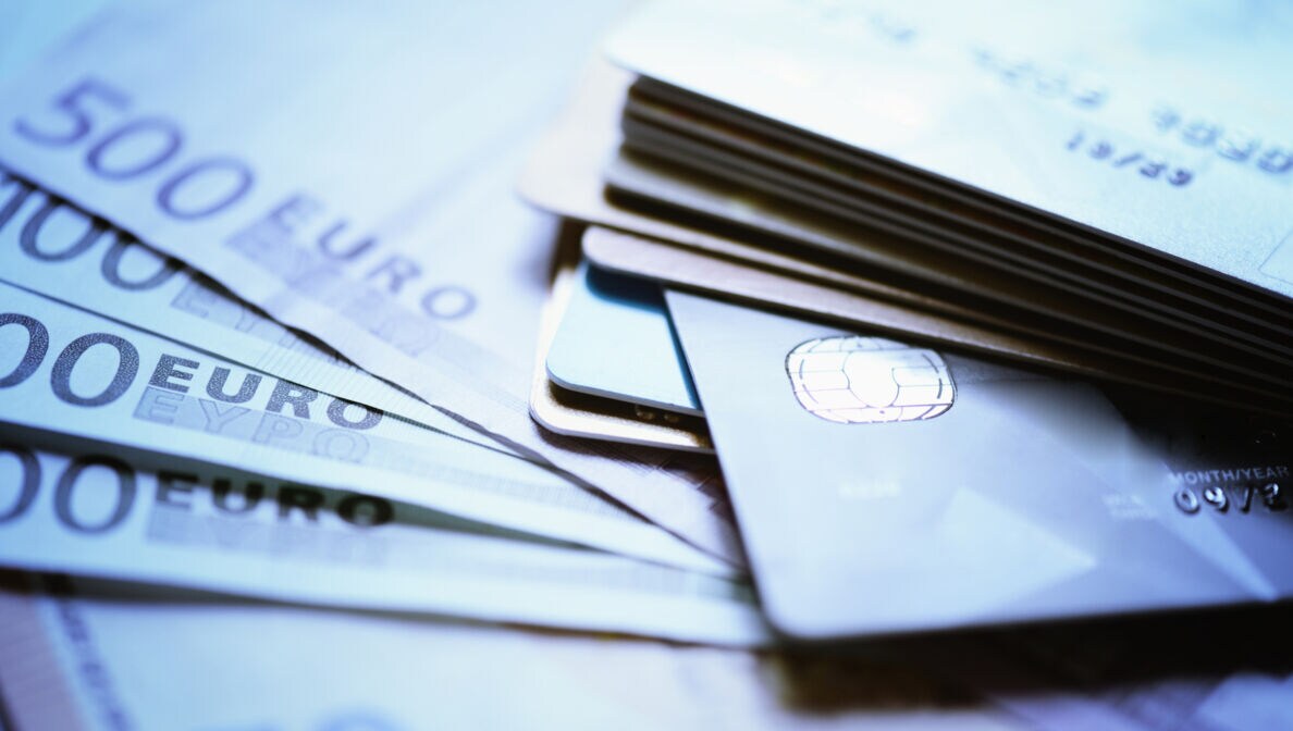 Mehrere Bankkarten liegen gestapelt auf Geldscheinen.
