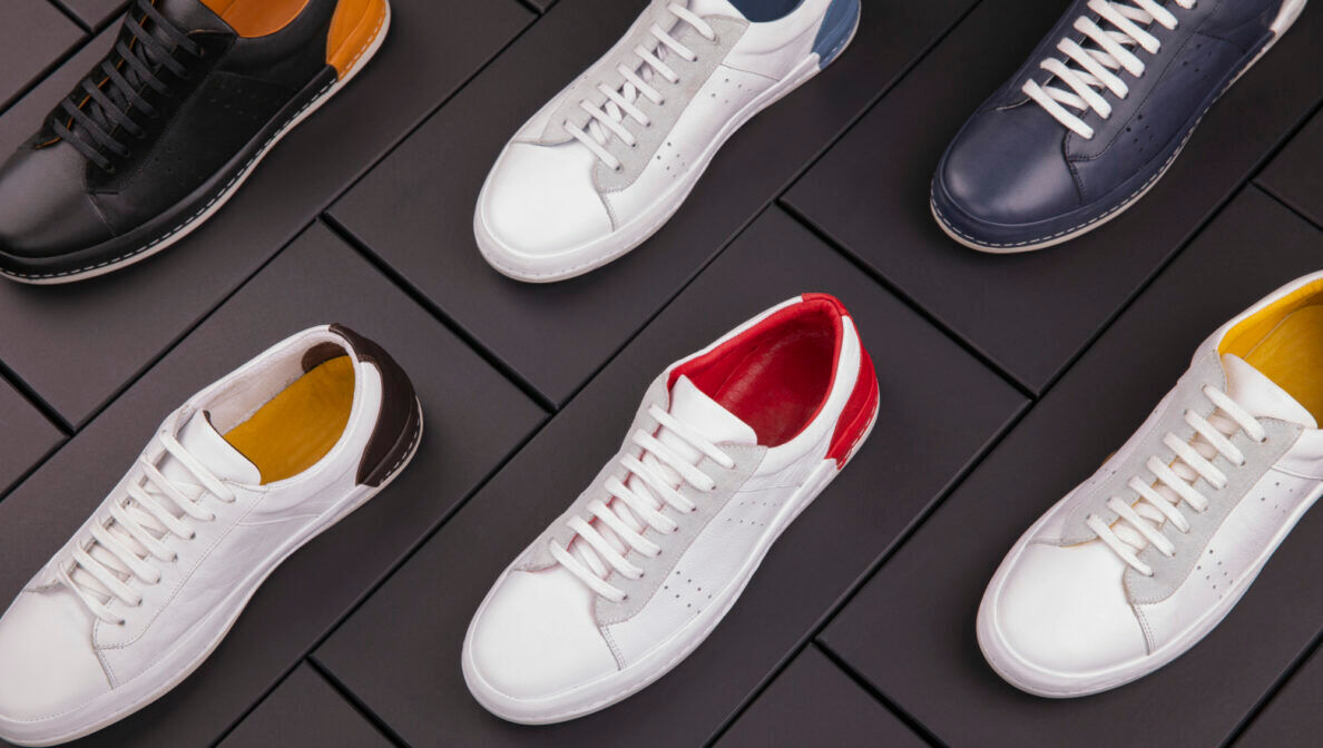 Eine Auswahl von Leder-Sneakern in verschiedenen Farben, die auf schwarzen Schuhkartons platziert sind.
