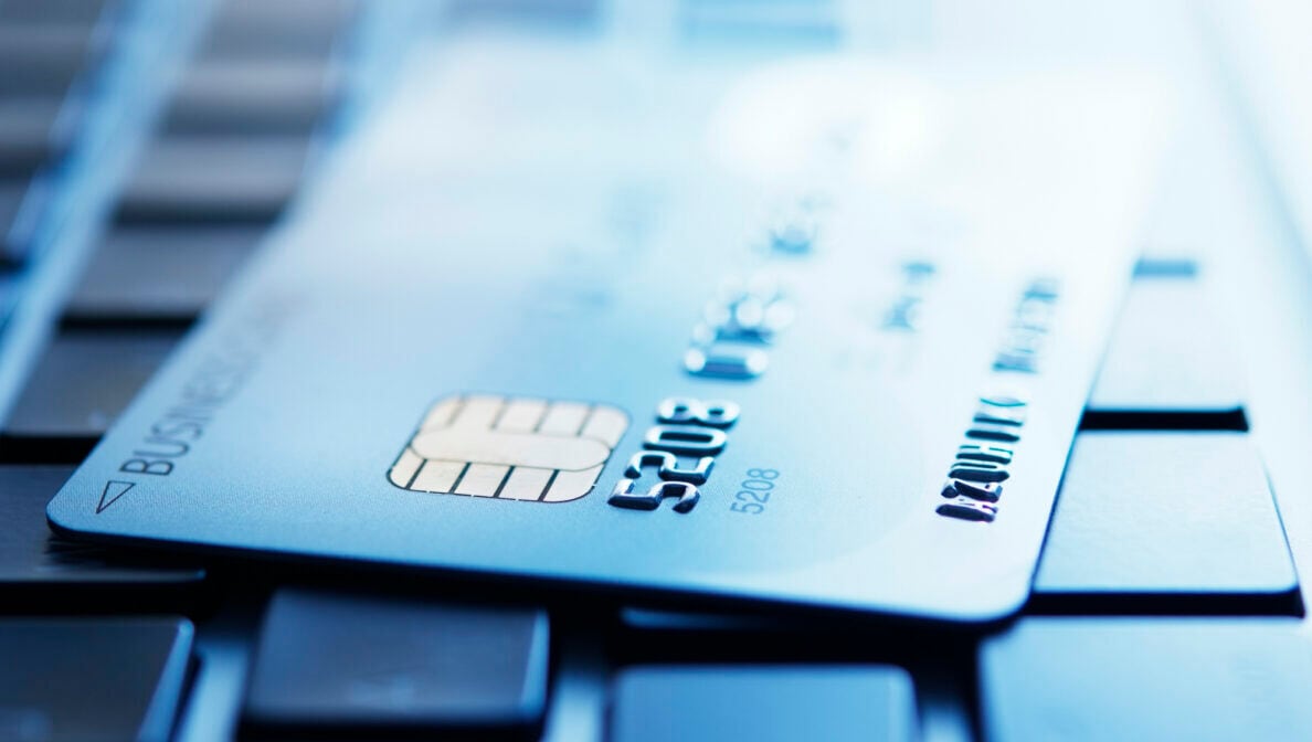 Blau getöntes Foto einer Kreditkarte, die auf der Tastatur eines Laptops liegt und deren Kreditkartennummer erkennbar ist.