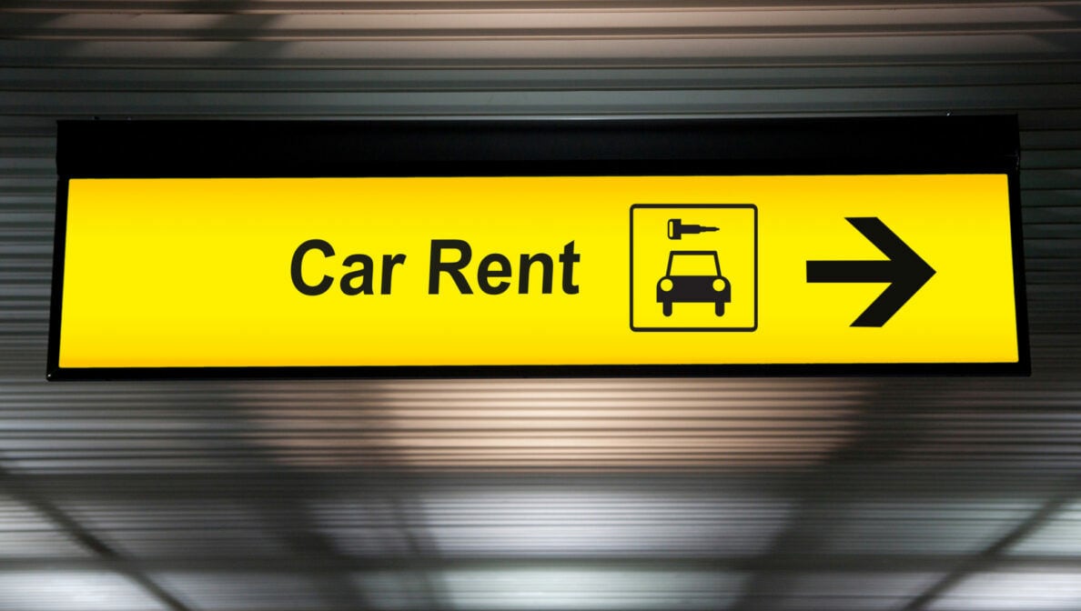 Ein gelbes Leuchtschild mit der Aufschrift „Car Rent“ sowie einem Symbol von Auto und Schlüssel.