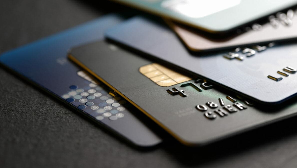 Ein Stapel unterschiedlich farbiger Kreditkarten vor dunklem Hintergrund.