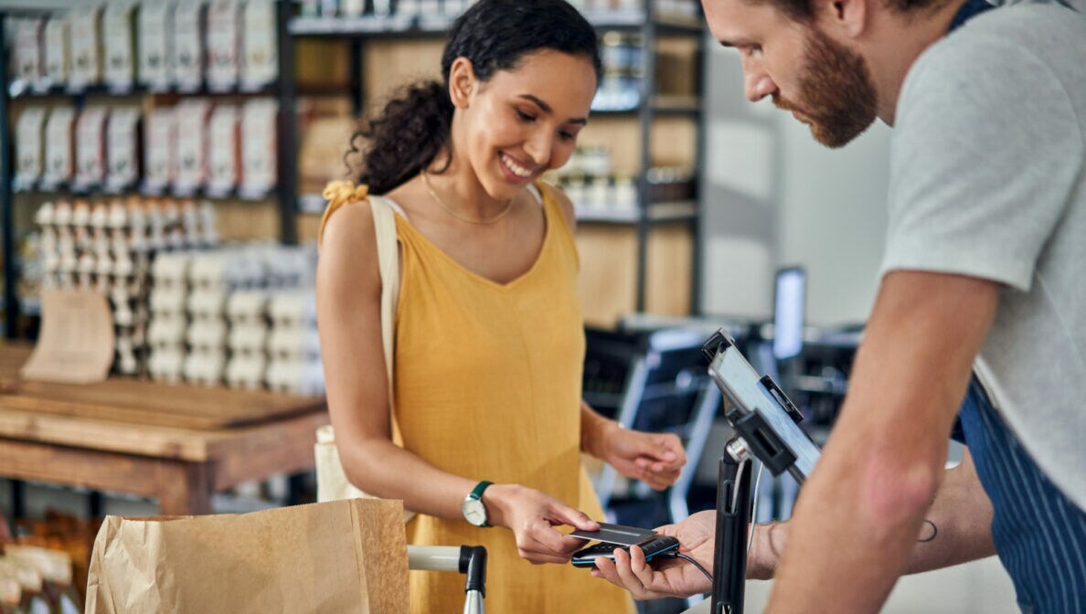 Eine junge Frau hält eine Kreditkarte an ein Kartenlesegerät.