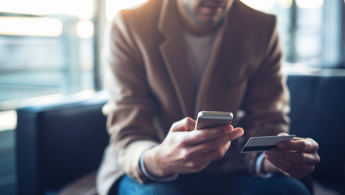 Nahaufnahme einer Person, die ein Smartphone in der einen Hand hält und eine Kreditkarte in der anderen.