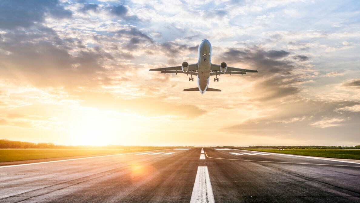 Ein Flugzeug startet bei Sonnenuntergang von der Landebahn.