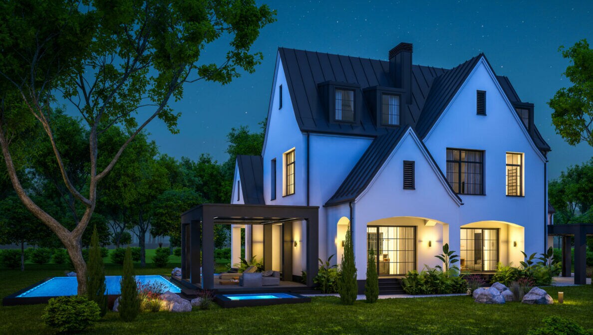 Ein beleuchtetes Einfamilienhaus bei Nacht.