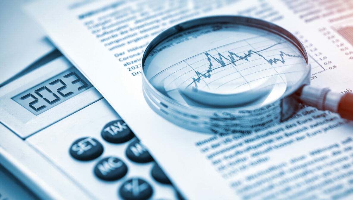 Eine Lupe liegt auf einem Blatt Papier mit Aktienkursen.