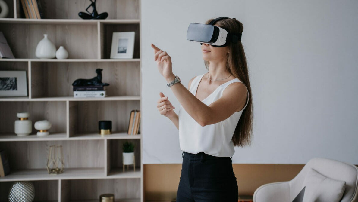 Eine Person steht in einem Wohnzimmer und trägt eine Virtual-Reality-Brille.