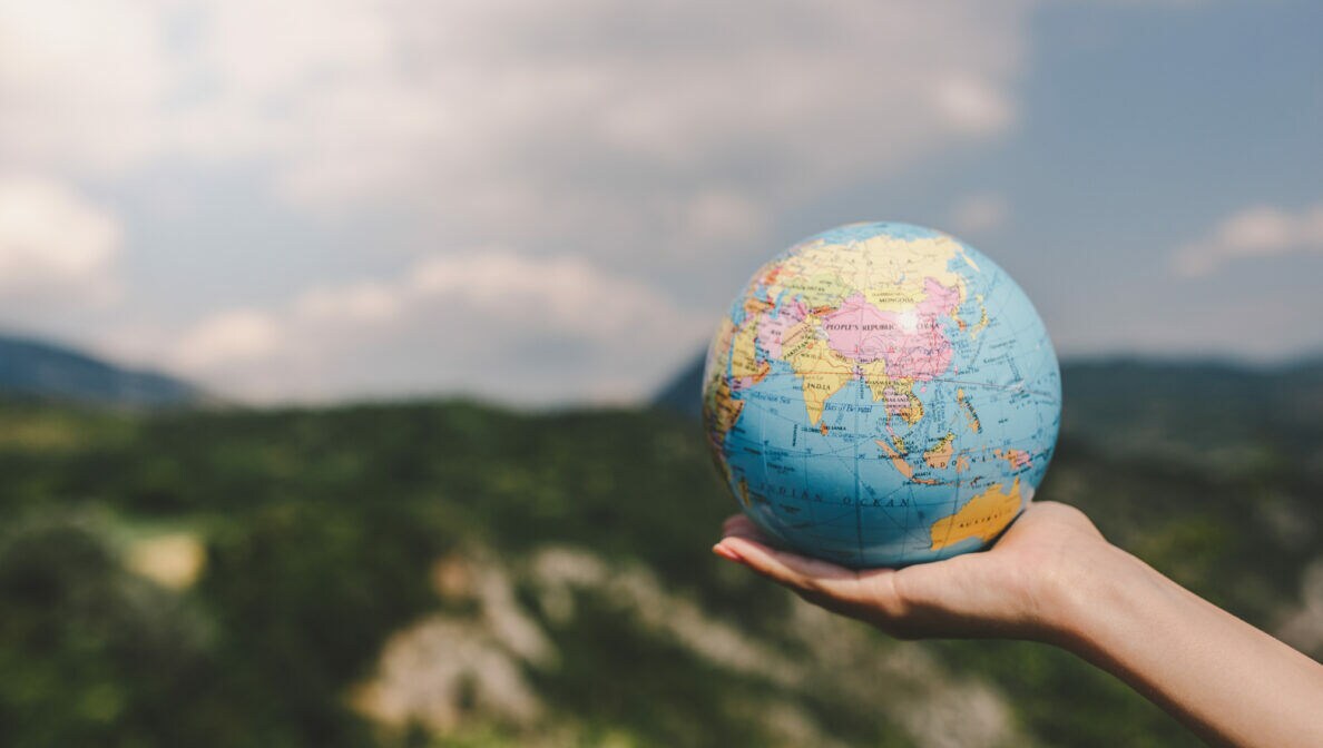 Nahaufnahme einer Hand, die einen kleinen Globus hält.