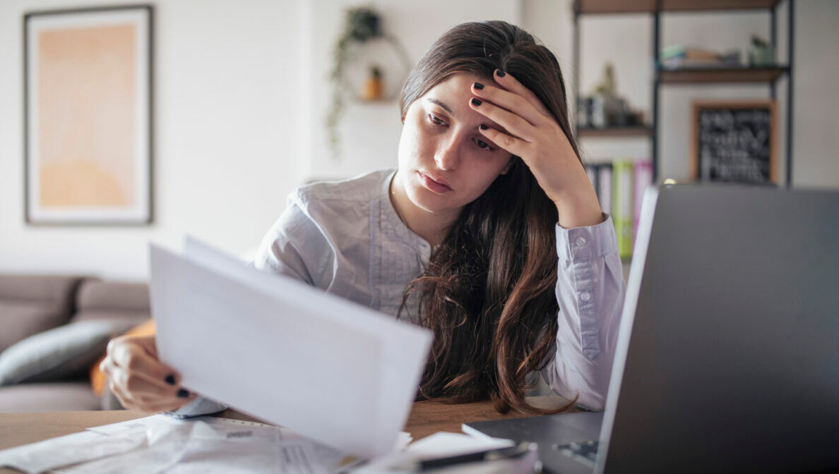 Eine Frau sitzt vor einem Laptop mit vielen Rechnungen und Bons.