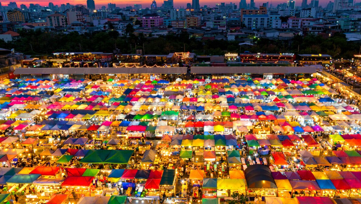 Der Nachtmarkt in Bangkok mit beleuchteten Ständen und bunten Zeltdächern.