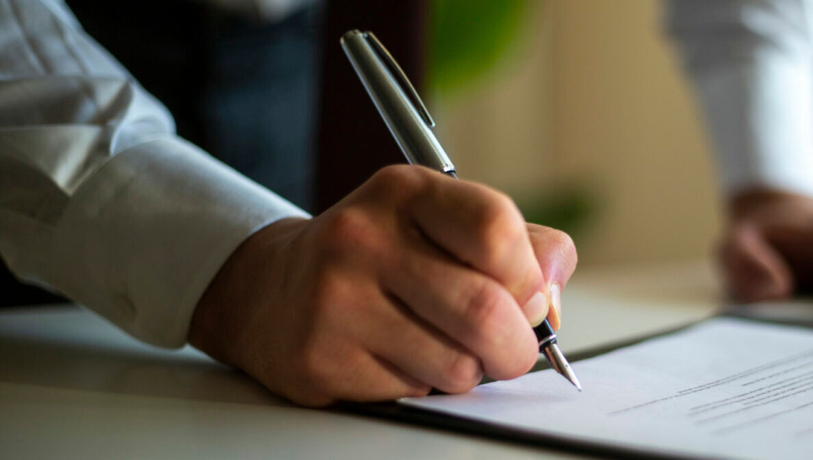 Eine Person unterschreibt ein Schriftstück mit einem Füllfederhalter.